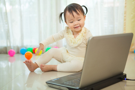 小亚洲女孩玩手提电脑在家里