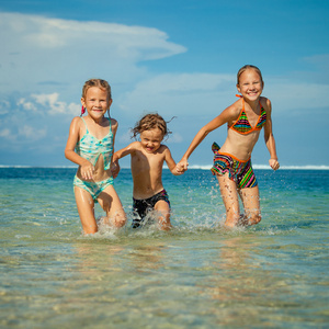 三个快乐的孩子在一天时间在沙滩上玩