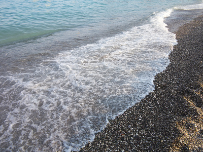 黑暗的鹅卵石海滩和蓝色的海浪