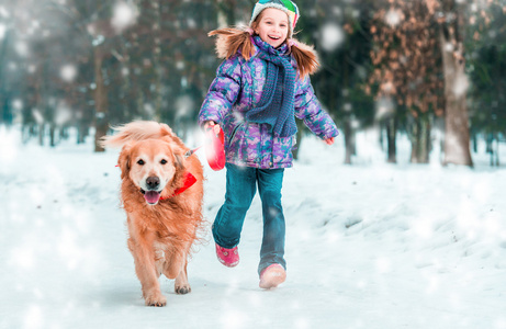 小女孩用狗在冬天的雪