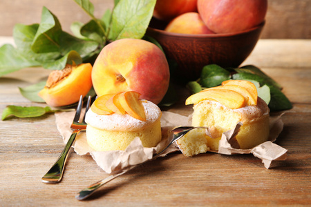 好吃的迷你蛋糕与新鲜的桃子，木制的桌子上