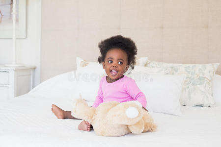 穿着粉红色婴儿服的女婴坐在床上