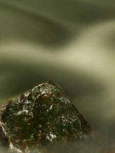 在山间溪流的湿的巨石。清澈的水通过长时间曝光，反射在水位模糊