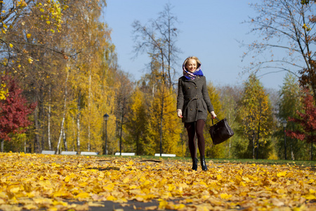 年轻女子走在秋天的公园
