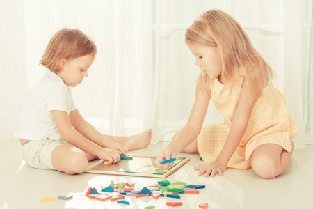 两个孩子玩木镶嵌在他们的房间在地板上