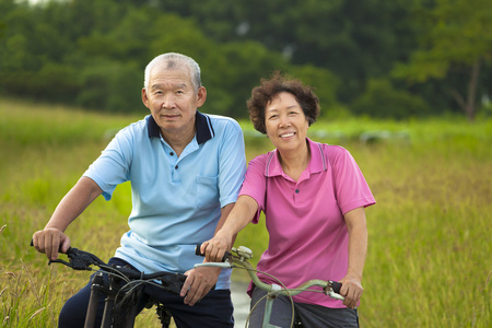 快乐的亚洲老年人对夫妇在公园里骑自行车