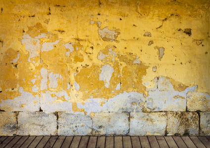 粗糙，剥落的黄色油漆和木地板的墙