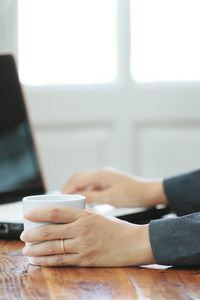 女商人拿一杯咖啡使用便携式计算机