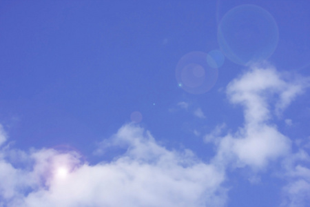 在蓝天上的白云与镜头耀斑背景
