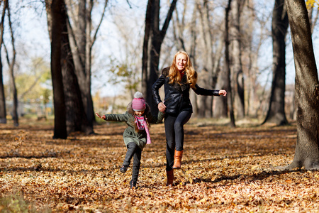年轻的母亲和她的女儿在秋天的公园