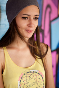 十几岁的女孩，与在涂鸦墙微笑顶灰色的帽子