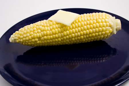 玉米和黄油在盘子上图片
