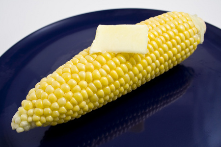 玉米和黄油在盘子上图片