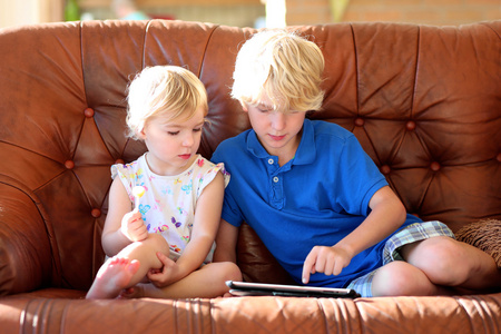 弟弟和妹妹玩平板电脑在沙发上