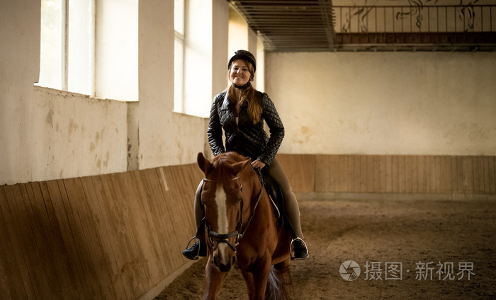 女人美丽的棕色骑马在室内manege