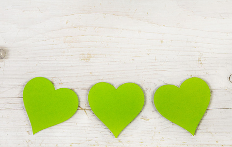 三个苹果绿色的心，在白色破旧风格木制背景