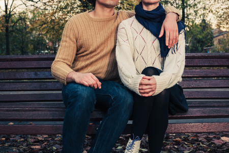 年轻夫妇坐在公园的长椅上