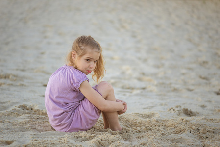坐在沙滩上的小伤心女孩