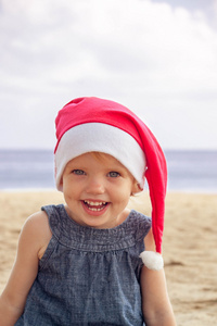 可爱的女孩在圣诞老人的帽子在热带鱼的开心