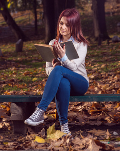 大学女孩坐在公园，读一本书