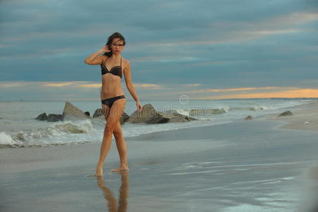 一个穿着比基尼的迷人的年轻女子在海滩上摆姿势