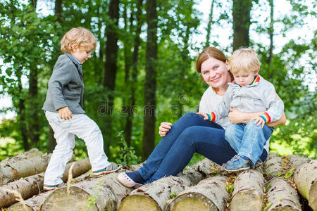 年轻的母亲和两个小孩在夏日森林里玩得很开心