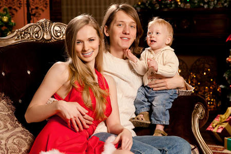 圣诞树旁快乐微笑的年轻家庭庆祝新的一天