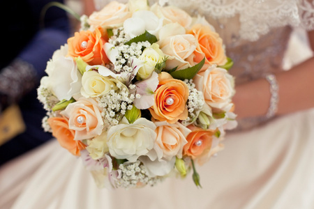 柔和的婚礼花束与橙色玫瑰在手中