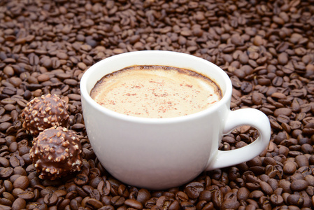 杯咖啡和咖啡豆背景上的糖果