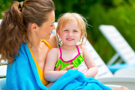 快乐宝贝女孩与母亲坐在日光浴浴床的肖像