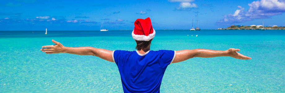 在热带海滩上的红色圣诞帽的年轻人