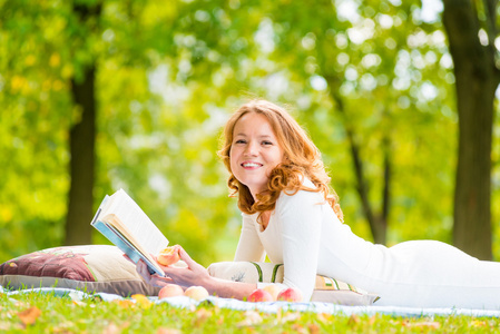 在夏天公园的草地上，一本好书的女孩笑