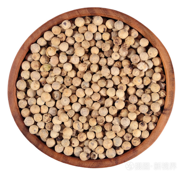 白胡椒种子在一个木碗在一张白纸