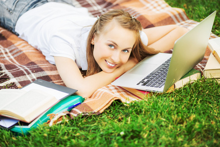 学生女人躺在草地上，笔记本电脑