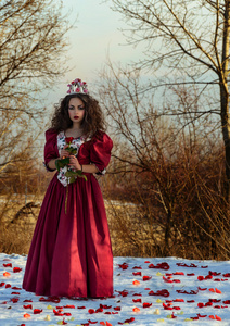 美丽的女孩，在葡萄酒红色礼服与一朵玫瑰