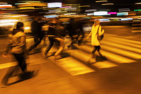 人在运动模糊的夜晚穿越城市的街道