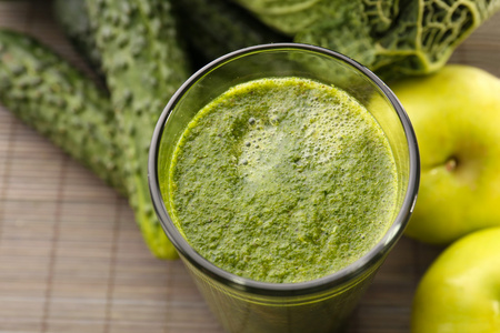 绿色新鲜健康果汁与苹果 蔬菜上竹垫背景