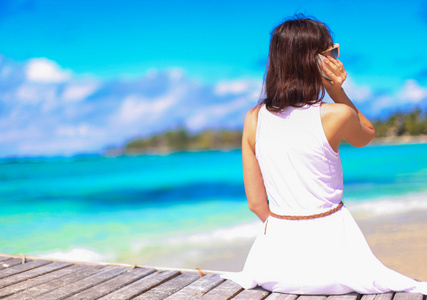 在热带海滩度假期间谈电话的年轻女子