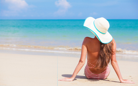 游泳衣和太阳镜躺在海滩上的年轻女子