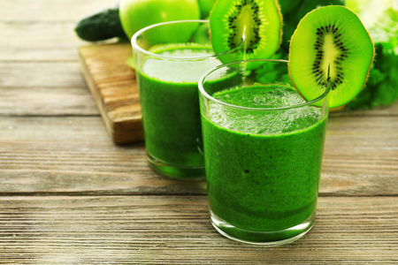 绿色新鲜健康果汁与水果和蔬菜切菜板和木桌背景