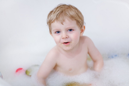 可爱的金发幼儿男孩玩水由以浴
