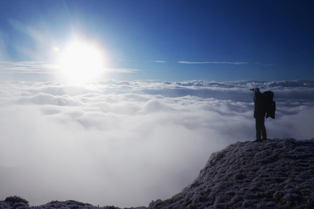 与大背包旅游是站在角度和看进迷雾笼罩的山谷。阳光明媚的冬日