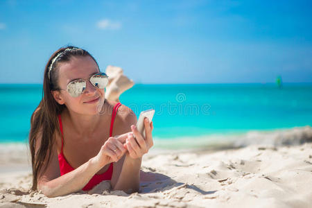 在异国情调的海滩上拿着手机的年轻女人