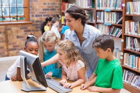 可爱的学生和老师在图书馆看电脑