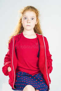 一个穿着红色夹克和圆点短裙的红头发白人小女孩的画像