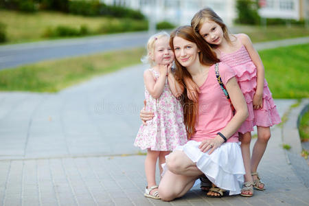 年轻漂亮的妈妈和两个女儿拥抱在一起