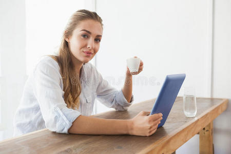 金发美女一边喝咖啡一边用平板电脑