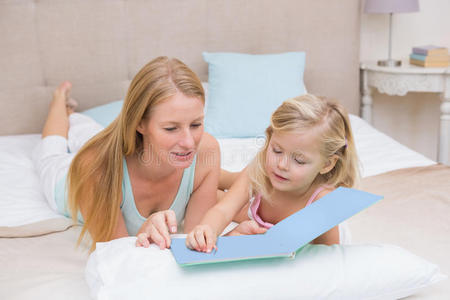 可爱的小女孩和妈妈在床上看书