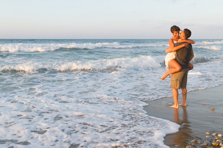 对年轻的夫妇喜欢在黄昏时在朦胧的海滩上散步