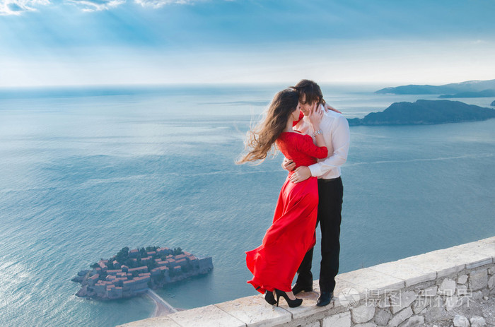 浪漫拥抱夫妇在蓝色的大海,在圣燕姿旁边
